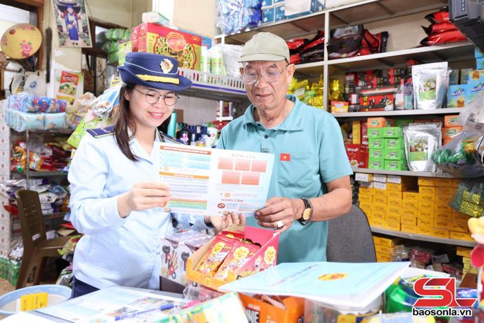 Cán bộ Đội QLTT số 5 phát tờ rơi, tuyên truyền về phòng, chống hàng giả cho nhân dân.