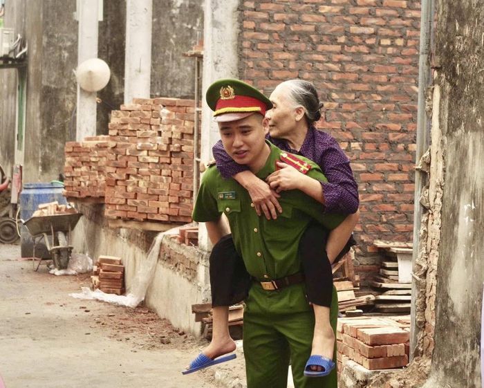 Do đi lại khó khăn, bà Dư Thị Hy đã được chiến sĩ công an xã Ứng Hòa hỗ trợ đưa đến dự lễ khởi công. Ảnh: Như Thành