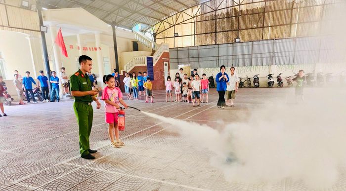 Trẻ em thực hành cách sử dụng bình chữa cháy dưới sự hướng dẫn của lực lượng chức năng. Ảnh: HM.