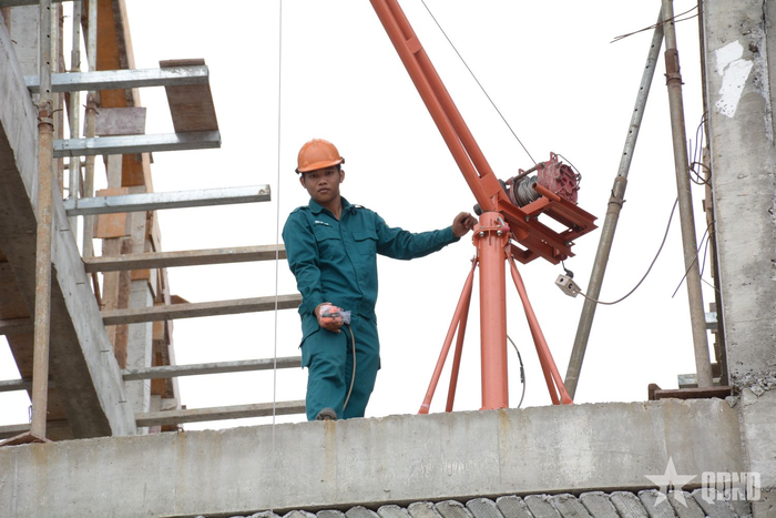 Chiến sĩ dân quân sử dụng máy tời đưa xi măng, sắt thép lên những tầng cao.