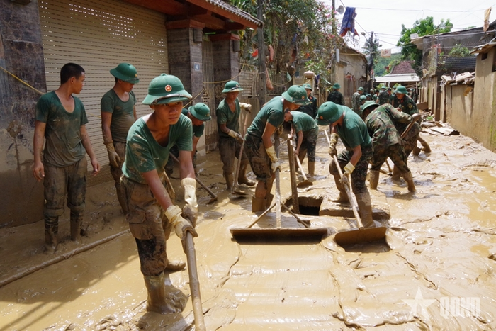 Bộ đội nỗ lực dọn bùn đất ra khỏi đường làng, khu dân cư. Ảnh: qdnd.vn
