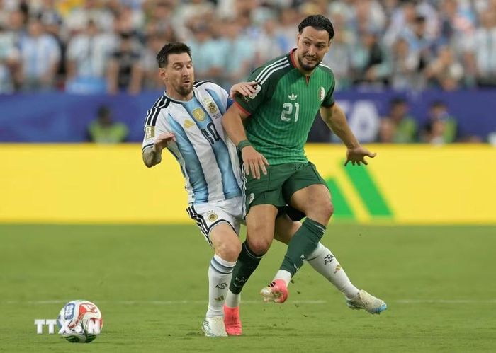 Pha tranh bóng giữa tiền đạo Argentina Lionel Messi (số 10) và hậu vệ Algeria Ramy Bensebaini (số 21). (Ảnh: AFP/TTXVN)