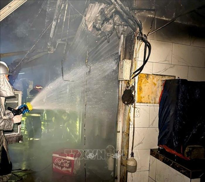 Lực lượng Cảnh sát PCCC&amp;CNCH triển khai đội hình phun nước dập tắt đám cháy tại ki-ốt kinh doanh đồ ăn uống trong chợ Mỹ Đình, đêm 16/6. Ảnh: TTXVN phát.