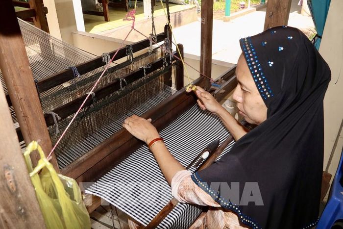 Nghệ nhân Chăm (xã Châu Phong, tỉnh An Giang) tỉ mỉ thực hiện các công đoạn dệt thổ cẩm trên khung dệt thủ công truyền thống. Ảnh: Thanh Sang-TTXVN