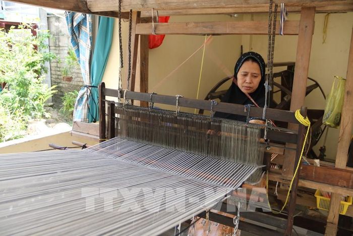 Nghệ nhân Chăm (xã Châu Phong, tỉnh An Giang) tỉ mỉ thực hiện các công đoạn dệt thổ cẩm trên khung dệt thủ công truyền thống. Ảnh: Thanh Sang - TTXVN