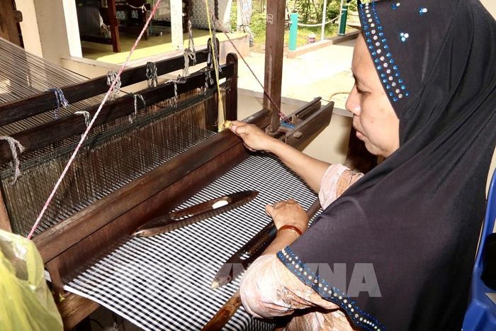 Nghệ nhân Chăm (xã Châu Phong, tỉnh An Giang) tỉ mỉ thực hiện các công đoạn dệt thổ cẩm trên khung dệt thủ công truyền thống. Ảnh: Thanh Sang-TTXVN