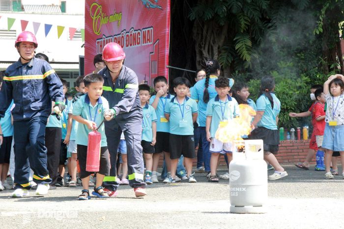 Các em thiếu nhi thực hành sử dụng bình bột chữa cháy để xử lý tình huống cháy giả định. Ảnh: Nga Sơn
