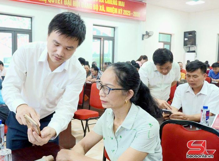 Cán bộ xã Chiềng Mai hỗ trợ cài đặt sử dụng ứng dụng Sổ tay đảng viên điện tử.