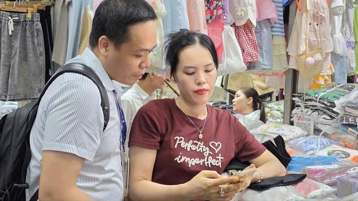 Cán bộ VNPT Huế hướng dẫn tiểu thương chợ Đông Ba thao tác thanh toán