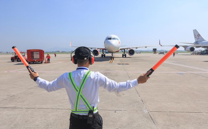 Nhân viên đánh tín hiệu tàu bay thực hiện nhiệm vụ trên sân đỗ Cảng hàng không quốc tế Nội Bài trong điều kiện thời tiết nắng nóng.