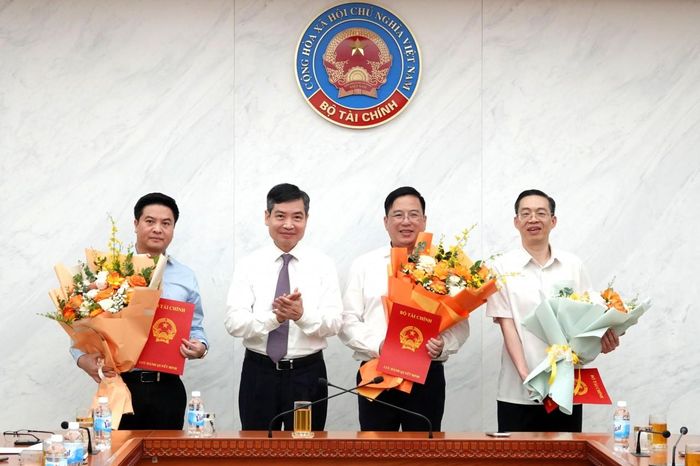 Thứ trưởng Tạ Anh Tuấn trao quyết định và tặng hoa chúc mừng ông Trịnh Đức Trọng (ngoài cùng bên trái), ông Đặng Quyết Tiến (thứ hai bên phải), ông Nguyễn Quốc Hưng (ngoài cùng bên phải) được điều động, bổ nhiệm chức vụ mới. Ảnh: Hoàng Dung