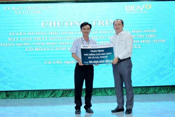 Ông Trần Quang Thái (bên trái), Ủy viên Ban Thường vụ Đảng ủy, Phó Chủ tịch UBND xã Củ Chi, đại diện địa phương tiếp nhận bảng tượng trưng học bổng từ đại diện đơn vị tài trợ.