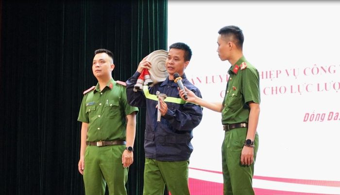 Cán bộ Công an thành phố Hà Nội hướng dẫn thao tác lăng vòi chữa cháy. Ảnh: Hoa Thành
