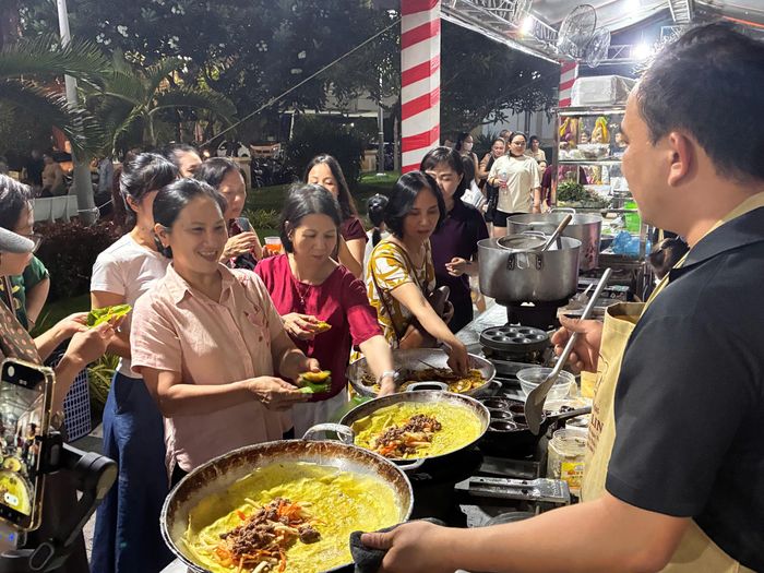  Du khách vui thích khi thưởng thức bánh xèo tại khu ẩm thực. Ảnh: NHẪN NAM 