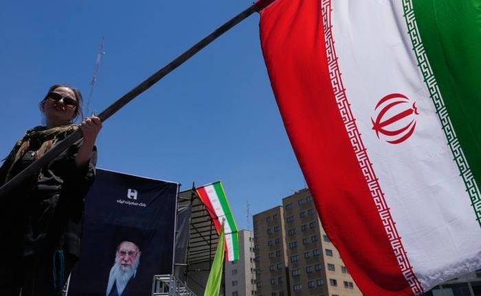 Một người phụ nữ vẫy cờ Iran tại trung tâm Tehran hôm 15-6. Ảnh: AP