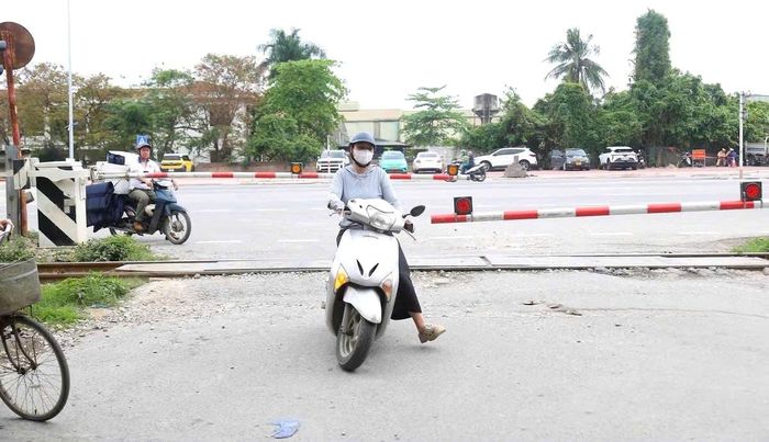 Người phụ nữ cố tình vượt qua khi gác chắn đã hạ và đèn đỏ cảnh báo bật sáng, bất chấp nguy hiểm. Ảnh: Lê Khánh.