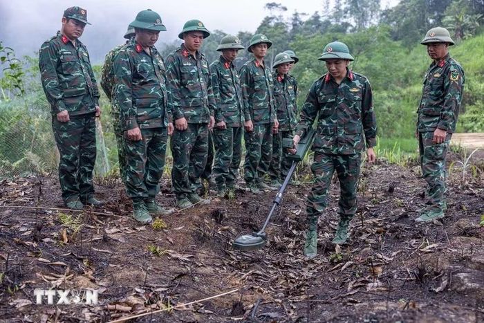 Các thành viên Đội tìm kiếm, quy tập hài cốt liệt sỹ tìm hiểu, sử dụng thành thục máy dò mìn để đảm bảo sạch bom mìn, vật liệu nổ trong khu vực trước khi tiến hành tìm kiếm. (Ảnh: Hoàng Hiếu/TTXVN)