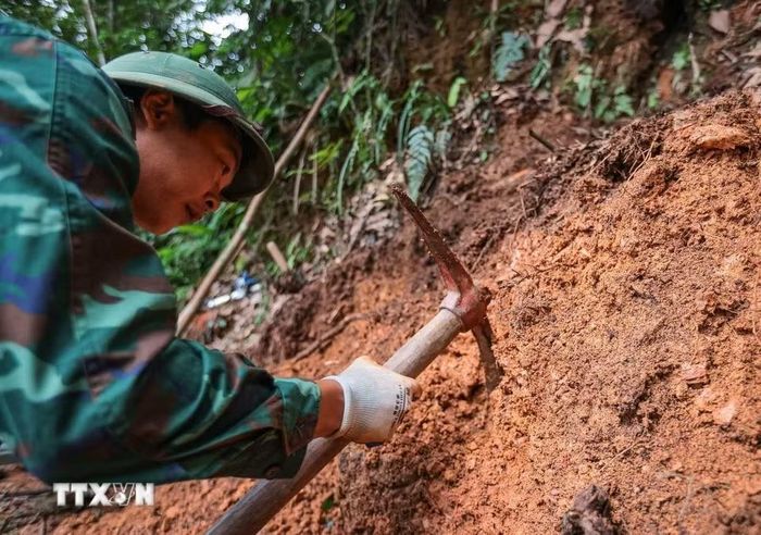 Các thành viên Đội tiến hành tìm kiếm tại khu vực nghi có hài cốt liệt sỹ tại xã Minh Tân. (Ảnh: Hoàng Hiếu/TTXVN)