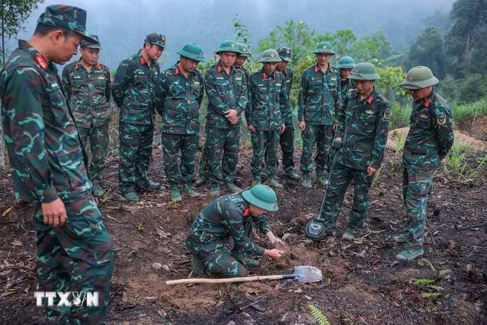 Các thành viên Đội tìm kiếm, quy tập hài cốt liệt sỹ sử dụng máy dò mìn để đảm bảo khu vực tìm kiếm "sạch" trước khi tiến hành tìm kiếm. (Ảnh: Hoàng Hiếu/TTXVN)
