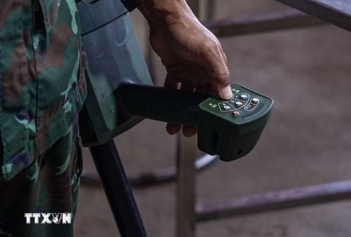 Thiếu tá quân nhân chuyên nghiệp Lê Văn Quyết hướng dẫn các thành viên trong Đội sử dụng máy dò mìn, đảm bảo an toàn khi tìm kiếm. (Ảnh: Hoàng Hiếu/TTXVN)