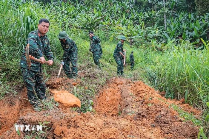 Các thành viên Đội tiến hành tìm kiếm tại khu vực nghi có hài cốt liệt sỹ tại xã Minh Tân. (Ảnh: Hoàng Hiếu/TTXVN)