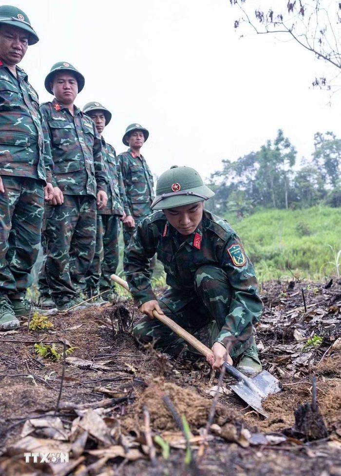 Các thành viên Đội tìm kiếm, quy tập hài cốt liệt sỹ tìm hiểu, sử dụng thành thục máy dò mìn để đảm bảo sạch bom mìn, vật liệu nổ trong khu vực trước khi tiến hành tìm kiếm. (Ảnh: Hoàng Hiếu/TTXVN)