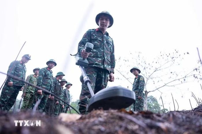 Các thành viên Đội tìm kiếm, quy tập hài cốt liệt sỹ tìm hiểu, sử dụng thành thục máy dò mìn để đảm bảo sạch bom mìn, vật liệu nổ trong khu vực trước khi tiến hành tìm kiếm. (Ảnh: Hoàng Hiếu/TTXVN)