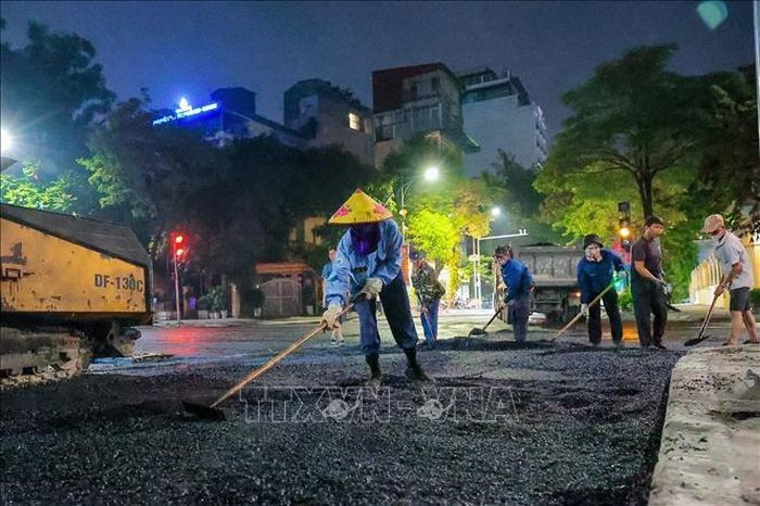 Công nhân cùng máy móc được huy động làm việc liên tục để thảm nhựa mặt đường trên tuyến phố Quang Trung.
