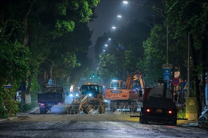Công nhân cùng máy móc được huy động làm việc liên tục để thảm nhựa mặt đường trên tuyến phố Quang Trung.