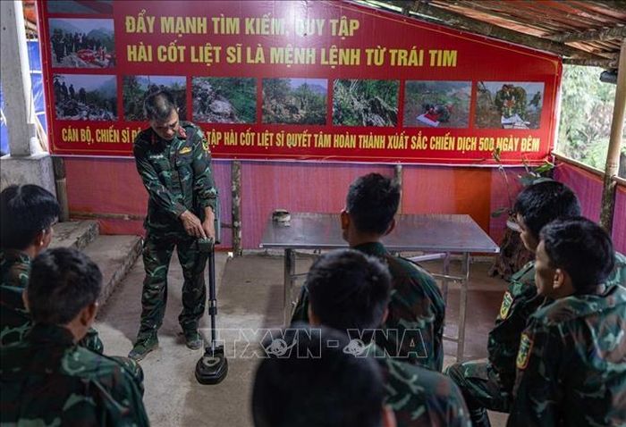 Thiếu tá quân nhân chuyên nghiệp Lê Văn Quyết hướng dẫn các thành viên trong Đội sử dụng máy dò mìn, đảm bảo an toàn khi tìm kiếm.