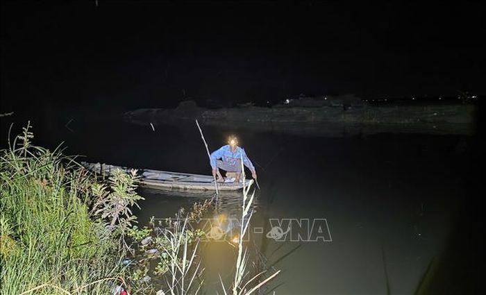 Lực lượng chức năng, cùng người dân tìm kiếm nạn nhân bị tai nạn đuối nước trong đêm. Ảnh: TTXVN phát