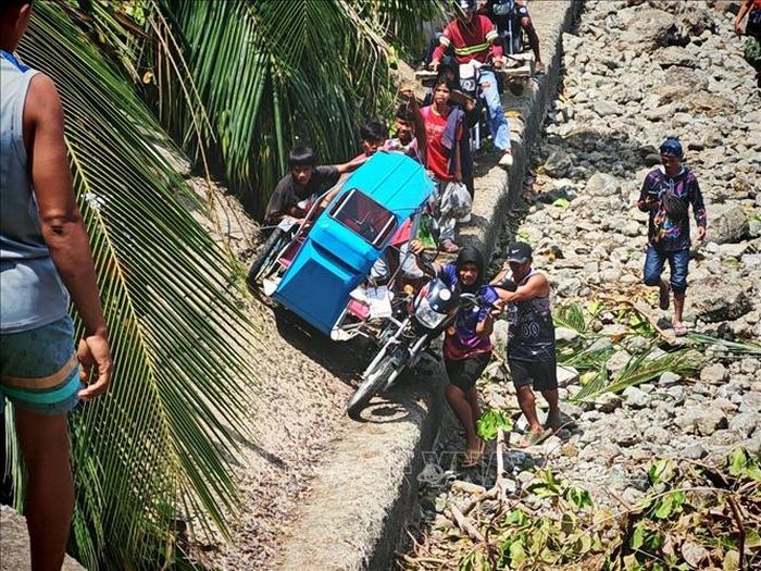 Người dân vượt qua một tuyến đường bị chặn do sạt lở đất tại Sarangani, Philippines, ngày 11/6/2026. Ảnh: THX/TTXVN
