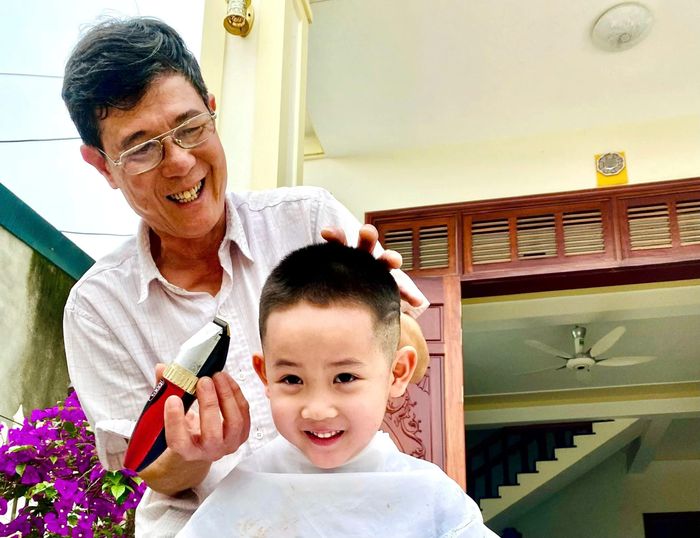 Niềm hạnh phúc hiện rõ trên gương mặt và nụ cười của ông Thắng khi được tự tay cắt tóc cho cháu.