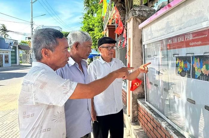  Người dân thôn Trung Tín 2 (xã Tuy Phước) nghiên cứu Đề án sắp xếp, tổ chức lại thôn được niêm yết công khai tại trụ sở thôn. Ảnh: M.MIÊN 
