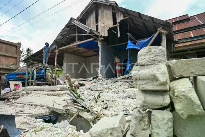  Người dân đứng trước ngôi nhà đã đổ sập do trận động đất ở làng Kamarora A, Sigi, Trung Sulawesi. Ảnh: ANTARA PHOTO 
