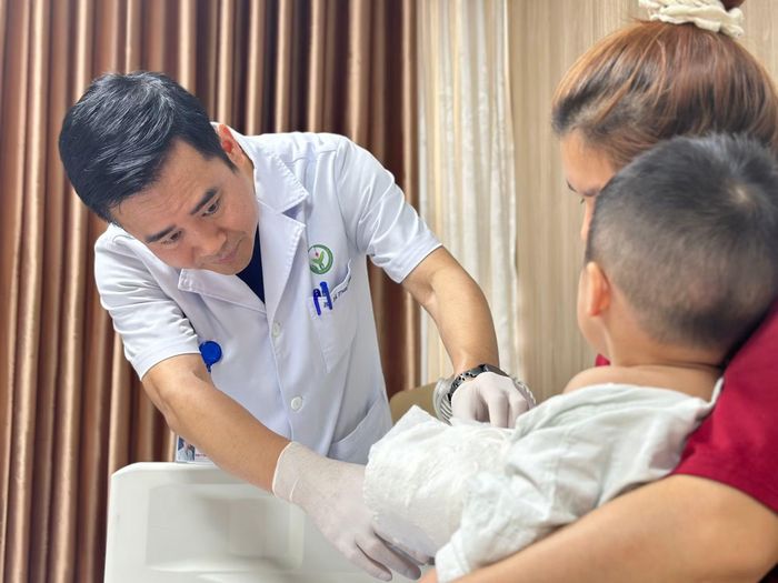 BS Vũ Trung Trực khám lại cho cháu bé sau phẫu thuật nối bàn tay.
