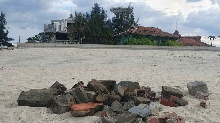 Hình ảnh du khách nước ngoài chủ động nhặt đá, gạch khỏi khu vực mép nước nhằm giảm nguy cơ mất an toàn cho người vui chơi trên bãi biển.