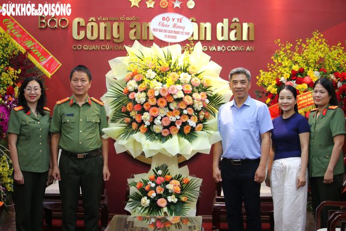 Phó Tổng Biên tập Báo Công an Nhân dân - Thượng tá Phan Đăng Trường - cùng đại diện Báo nhận hoa chúc mừng của Bộ Y tế.