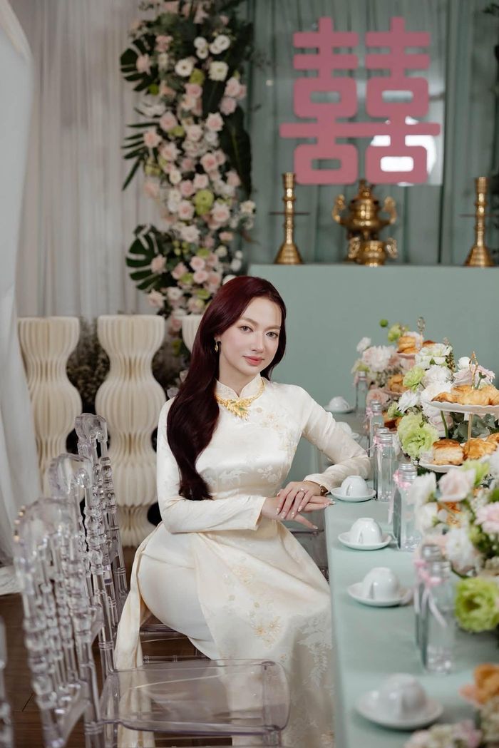  Trong lễ ăn hỏi, Xuân Nghi diện áo dài truyền thống, trang điểm nhẹ nhàng. Cô để kiểu tóc buông xõa, kết hợp thêm một số phụ kiện là trang sức. Không gian lễ ăn hỏi được trang hoàng tinh tế với hai tông màu xanh và hồng. 