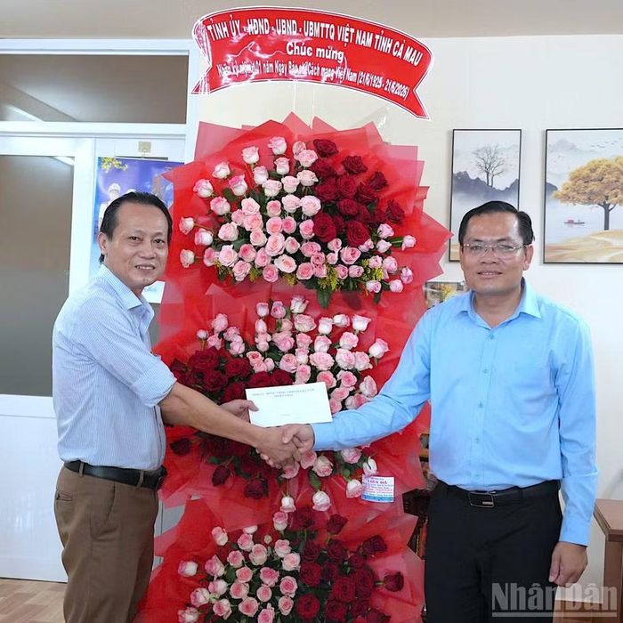 Phó Chủ tịch Ủy ban nhân dân tỉnh Cà Mau Ngô Vũ Thăng (bên phải) tặng hoa và quà chúc mừng đến Nhà báo Hữu Tùng, Trưởng đại diện Cơ quan Báo Nhân Dân tại Cà Mau.
