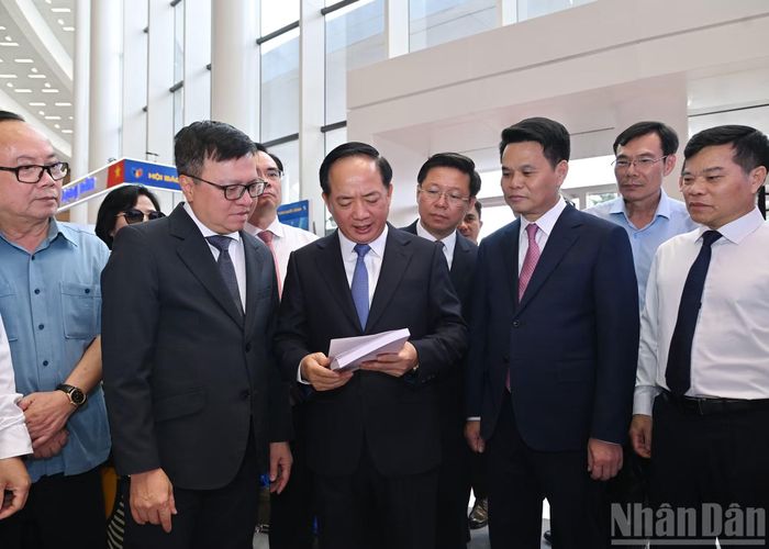Trưởng Ban Tuyên giáo và Dân vận Trung ương Trịnh Văn Quyết cùng các đại biểu nghe giới thiệu cuốn sách "Hoa vườn Bác" tại gian trưng bày của Báo Nhân Dân.