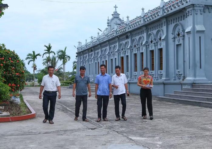 Cán bộ xóm 2, xã Nghĩa Sơn tới nhà thờ trên địa bàn để tuyên truyền, vận động người dân đồng thuận với chủ trương sắp xếp, tổ chức lại thôn, tổ dân phố. (Ảnh: Công Luật/TTXVN)