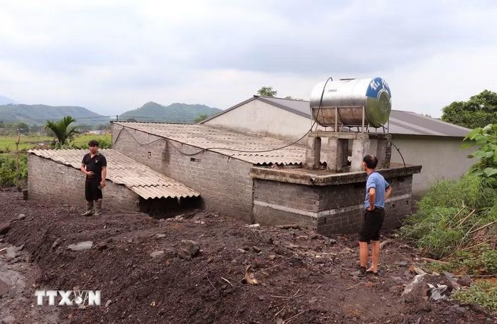 Lớp bùn đất dày phủ kín nhà ở, ảnh hưởng nghiêm trọng đến sinh hoạt của người dân. (Ảnh: Đức Thọ/TTXVN)