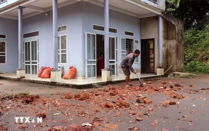 Người dân tranh thủ dọn dẹp đất đá, bùn đất để sớm khôi phục sinh hoạt. (Ảnh: Đức Thọ/TTXVN)