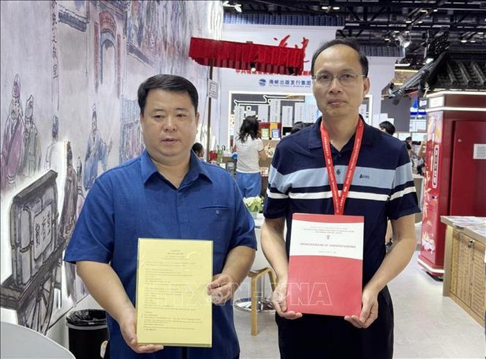 Giám đốc, Tổng biên tập Nhà xuất bản Văn hóa dân tộc Phùng Huy Cường (trái) trao đổi Biên bản ghi nhớ với Công ty TNHH Nhà xuất bản Khoa học Kỹ thuật Phúc Kiến (Trung Quốc).