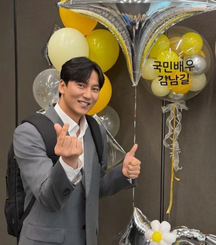Kim Nam Gil tươi cười tạo dáng bên bóng bay mang dòng chữ "Diễn viên Quốc dân Kim Nam Gil". Nguồn: StarnewsKorea)