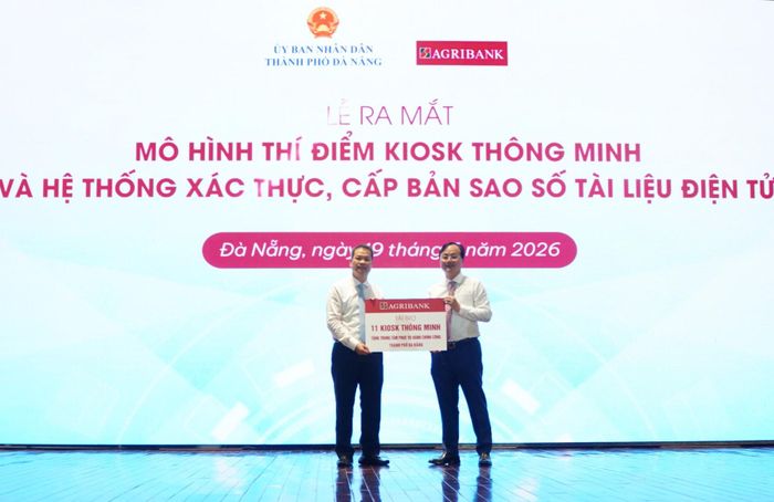 Chủ tịch UBND thành phố Nguyễn Mạnh Hùng (bên trái) tiếp nhận bảng tượng trưng trao tặng 11 Kiosk thông minh từ Bí thư Đảng ủy, Chủ tịch Hội đồng Thành viên Agribank Tô Huy Vũ. Ảnh: VINH ANH