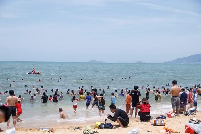 Dù thời tiết giữa trưa nắng gắt, song nhiều gia đình vẫn đưa con em và người thân xuống tắm biển với mong muốn đón nhận những điều tốt lành. Ảnh: H.P