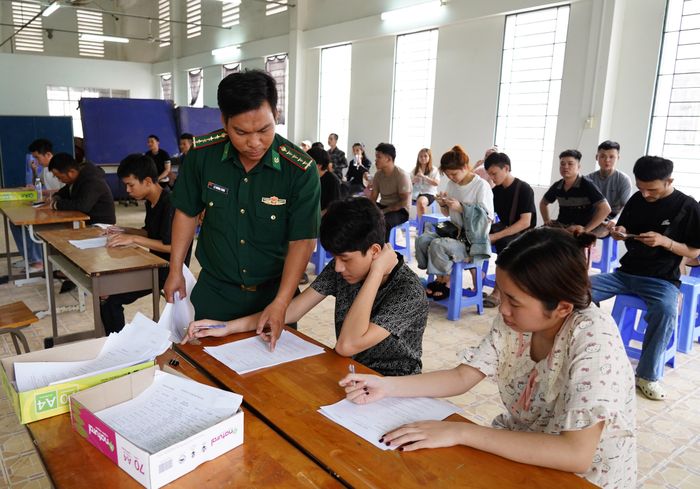 Cán bộ đồn Biên phòng cửa khẩu Quốc tế Tịnh Biên hướng dẫn công dân ghi bản khai cá nhân trước khi đưa về nơi cư trú. Ảnh: Tiến Vinh