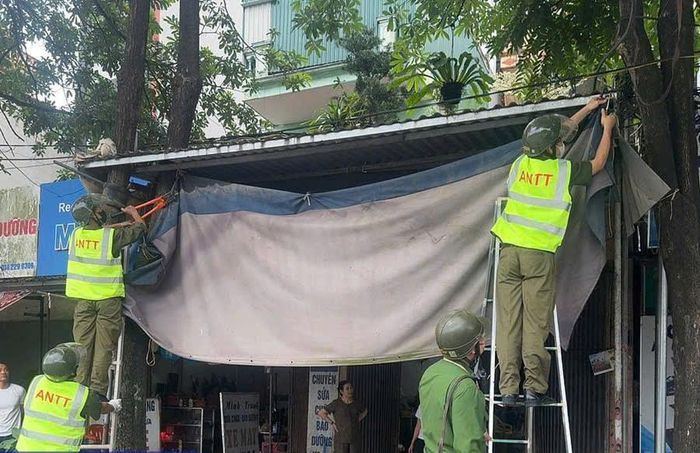 Lực lượng chức năng tổ chức tháo dỡ các mái che mái vẩy cơi nới lấn ra vỉa hè, hành lang giao thông. Ảnh: PV